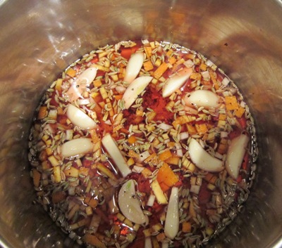 sliced garlic cloves, fennel seed, orange and lemon zests, and vinegar in a reflective pot